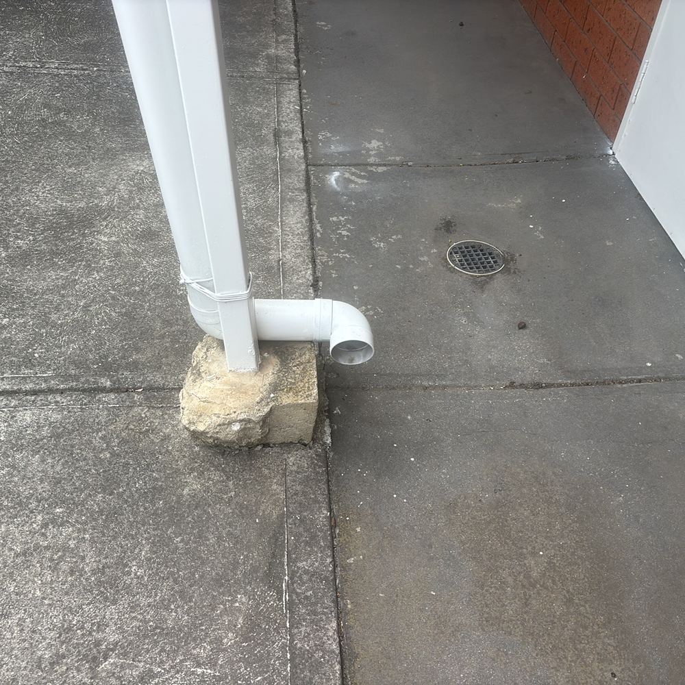 Ground staying wet beside the wall where a downpipe empties, found during a building and pest inspection in Braybrook